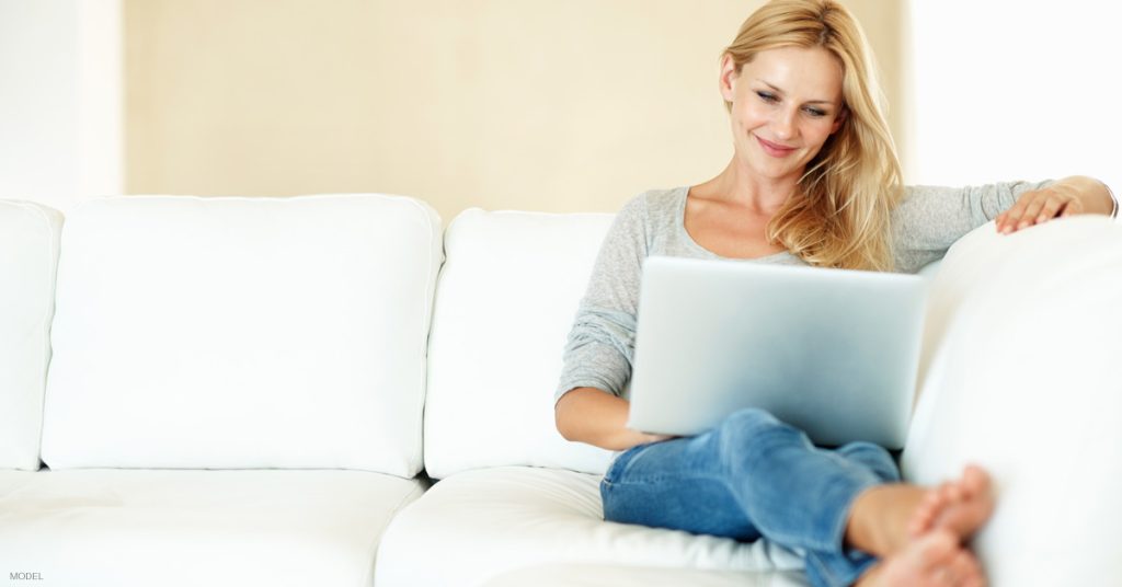 Woman sitting on couch reading answers to most common CoolSculpting questions